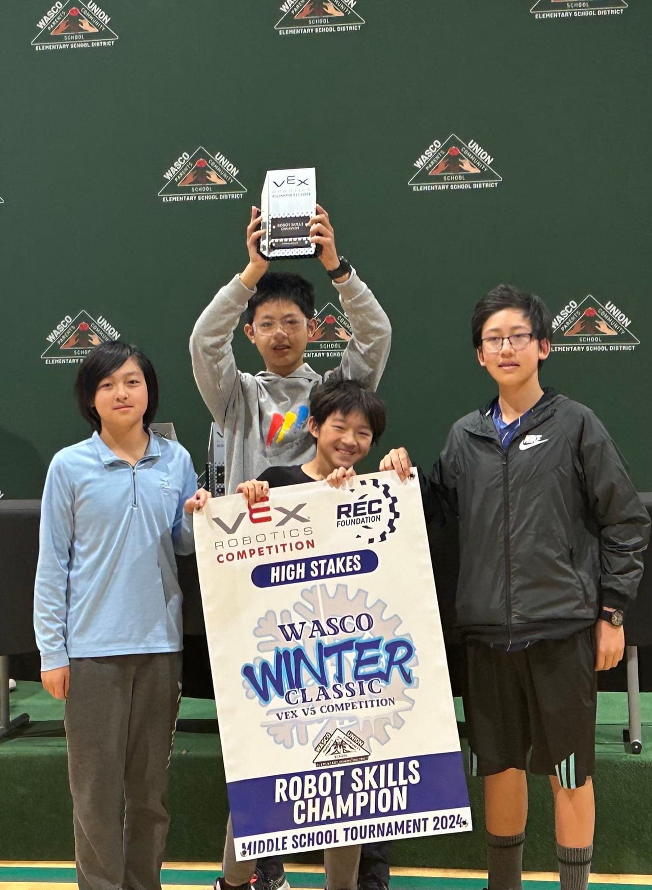 Edubot students holding a VEX IQ robot and trophy